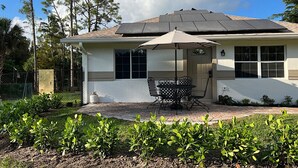 A house with a patio, a table and chairs, and a covered area. - Lovely Private Cottage, less than 5 miles to the beach!!! (Naples)