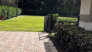 A paved pathway leading to a building with a green lawn and trees in the background. - Lovely Private Cottage, less than 5 miles to the beach!!! (Naples)