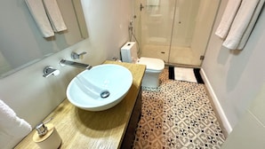 Une salle de bain avec un lavabo blanc, des toilettes et une cabine de douche en verre.