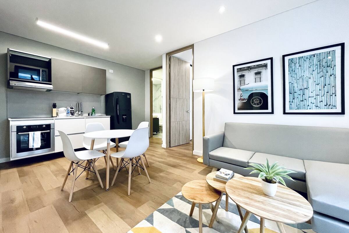 A modern apartment with a kitchen, dining area, and living room. It includes a sofa, a coffee table, and a TV.