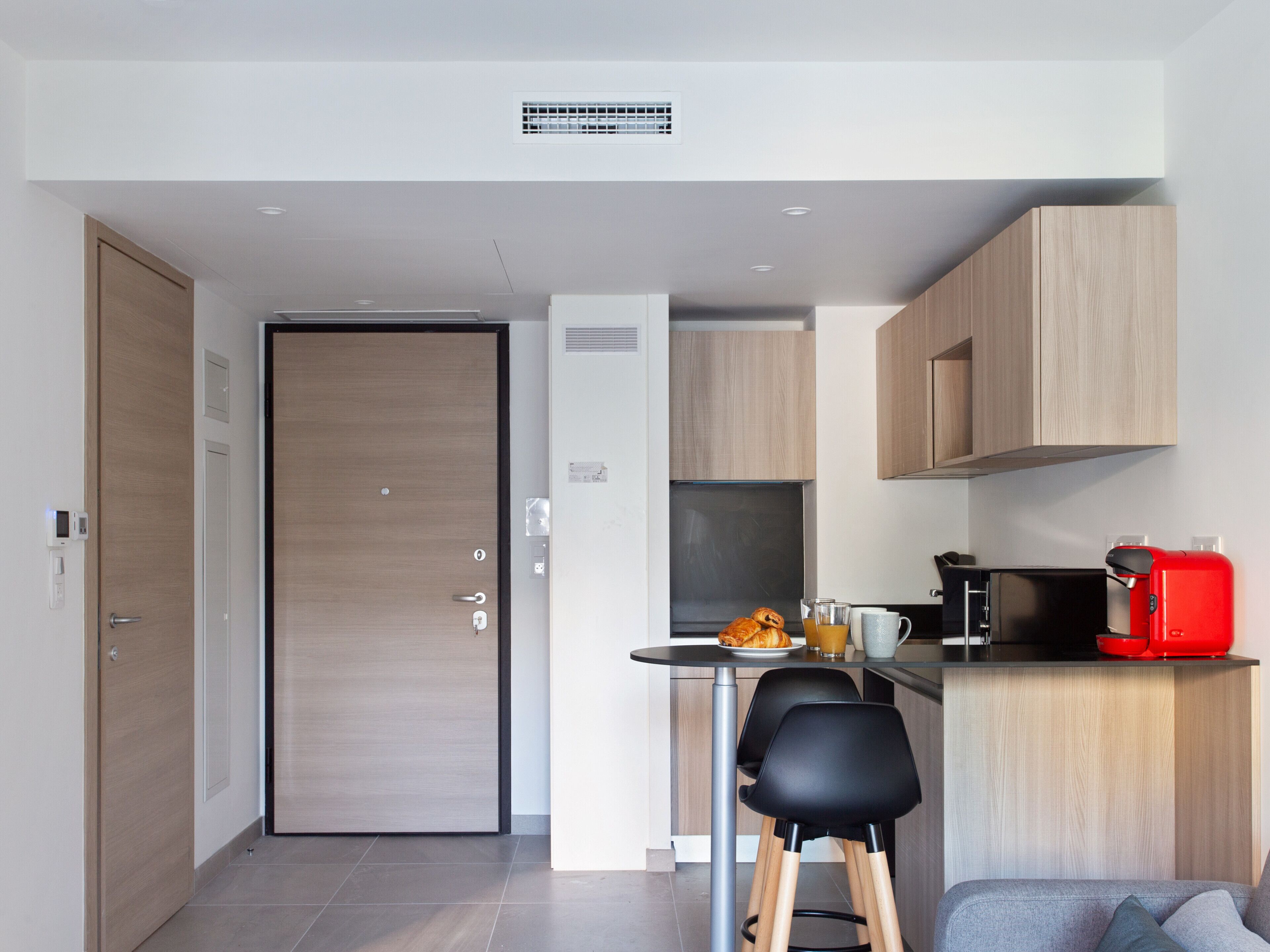 Una cucina moderna con zona pranzo, una macchina da caffè e un'apertura che dà su un'altra stanza.