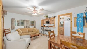 A cozy living area with a sofa, a dining table, and chairs. There is a kitchen area with wooden cabinets and a ceiling fan. - Cabin 1, Aspen Leaf Lodges, Near Grand Lake (Grand Lake)