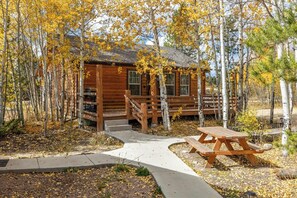A wooden cabin with a porch, surrounded by trees with yellow leaves. - 2BR, sleeps 6, moose country, Grand Lake, Cabin 4, nestled in aspens (Grand Lake)