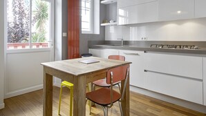 Una cocina moderna con armarios blancos, una mesa de madera y dos sillas.