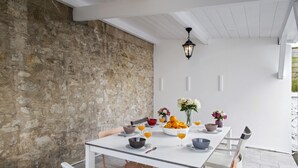 Un comedor con pared de piedra, mesa blanca y sillas.