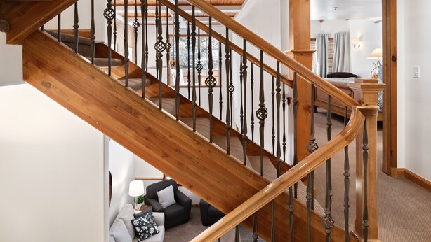 Una escalera de madera con diseño curvo que lleva a un dormitorio.