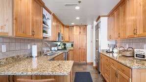 Una cocina moderna con armarios de madera, encimeras de granito y electrodomésticos de acero inoxidable, y un letrero de bienvenida.
