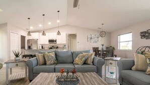 A modern living room with a grey sofa, a wooden coffee table, and pendant lighting. - Luxury Cape Coral Retreat Pool, Hot Tub, Beautiful Outdoor Oasis & Pet Friendly (Cape Coral)
