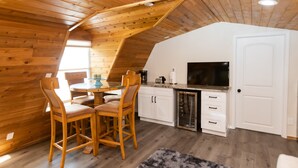 Eine gemütliche Küche mit Holzwänden und einem Essbereich mit zwei Holzsesseln und einem Tisch.