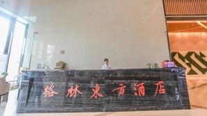A reception desk with a sign in a foreign language, a person standing behind it, and a modern interior design. - Greentree Eastern Nanjing Xianlin University City Hotel (Nanjing)