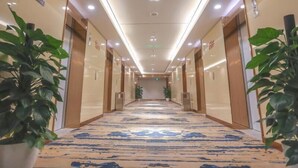 A hotel hallway with a marble-patterned floor, wooden doors, and potted plants. - Greentree Eastern Nanjing Xianlin University City Hotel (Nanjing)