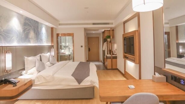 A modern hotel room with a bed, bedside table, lamp, TV, and a desk with a chair. - Greentree Eastern Nanjing Xianlin University City Hotel (Nanjing)