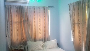A bedroom with a bed, curtains, and a window. - JiL Service Flat (Ibadan)