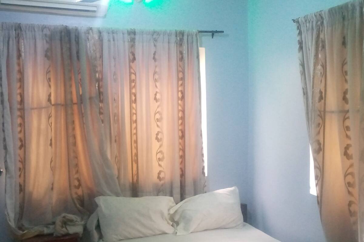 A bedroom with a bed, curtains, and a window.