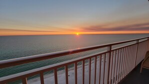 A sunset over the ocean with a balcony railing.