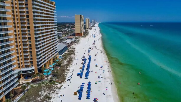 A coastal hotel with multiple floors, a beachside location, and a view of the ocean.