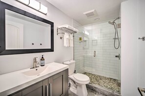 A modern bathroom with a large mirror, a sink, a toilet, and a glass-enclosed shower area. - Peaceful Forest Retreat by Mt. Baker Slopes! (Deming)