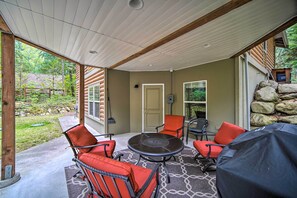 An outdoor patio with a round table and four red chairs, a grill, and a view of a wooded area. - Peaceful Forest Retreat by Mt. Baker Slopes! (Deming)