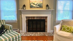 Una sala de estar con chimenea, sillones a rayas y un cuadro sobre la chimenea.
