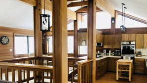 A spacious loft-style room with a wooden staircase, a kitchen area with modern appliances, and a dining area with a high wooden ceiling and large windows. - Our Lake Tahoe H💙ME<br> (Tahoe City)