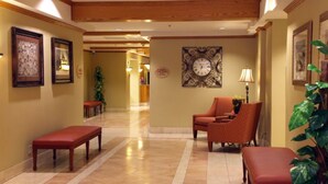 Um saguão de hotel com piso de mármore, um relógio na parede e áreas de estar.