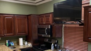 A kitchen with granite countertops, wooden cabinets, stainless steel appliances, and a flat-screen TV mounted above the oven. - Beautiful home and/or garage apartment, minutes from Oaklawn Park. (Hot Springs)