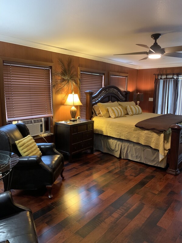 Une chambre à coucher comprenant un lit, une table de chevet, une lampe, une chaise et un ventilateur de plafond.