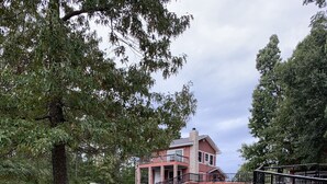 A two-story house with a balcony, surrounded by a fenced area and trees. - Beautiful home and/or garage apartment, minutes from Oaklawn Park. (Hot Springs)