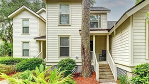 A two-story building with a front porch, a staircase, and a tree in the center. - Shipyard Cottage - Private Beach & Golf! Pet Friendly! Free beach chairs,towels. (Hilton Head Island)