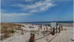 A sandy beach with a wooden fence and a sign. - Shipyard Cottage - Private Beach & Golf! Pet Friendly! Free beach chairs,towels. (Hilton Head Island)