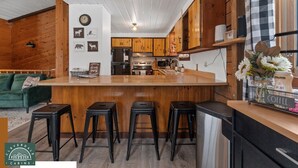 Una cocina moderna con armarios de madera, una isla central con taburetes altos y una zona de café.