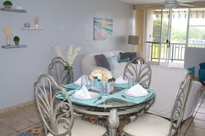 A dining area with a round glass table, metal chairs, and a white sofa in the background.