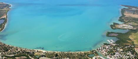An aerial view of a coastal area with a marina, residential buildings, and a large body of water.