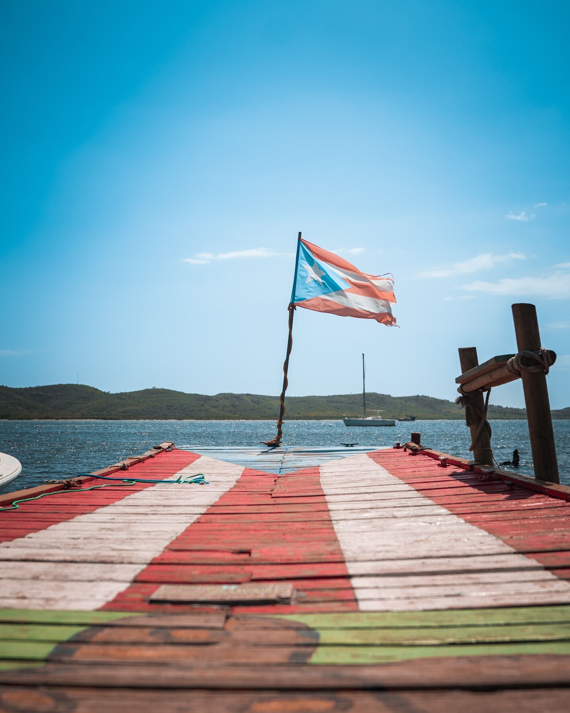 A wooden pier with a flag, a boat, and a distant shoreline.
