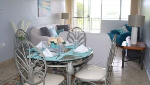 A dining area with a glass table, metal chairs, and a view of the outdoors through large windows.