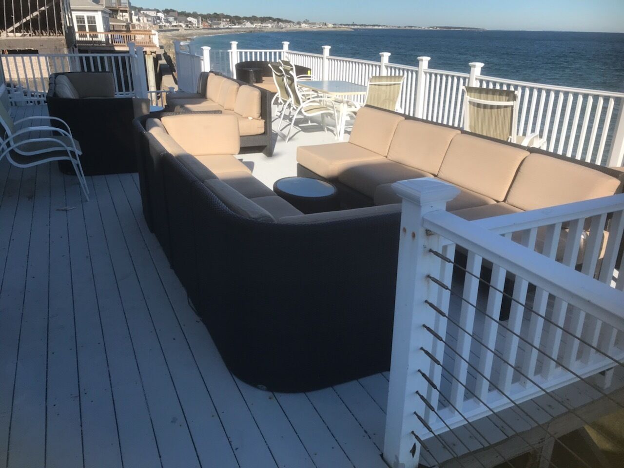 A deck with outdoor seating, including a sofa and chairs, and a railing.