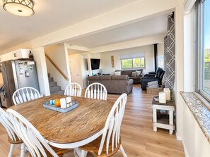 A spacious living area with a dining table, white chairs, a sofa, and a TV. - Lake View Casa (Fort Collins)