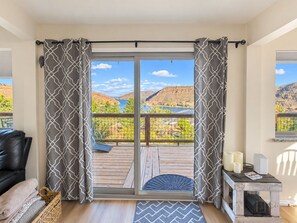 A room with a sliding glass door leading to a balcony with a view of a lake and mountains. - Lake View Casa (Fort Collins)
