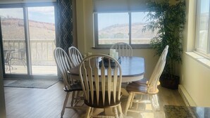 A dining area with a table and chairs, a ceiling light fixture, and a view through large windows. - Lake View Casa (Fort Collins)