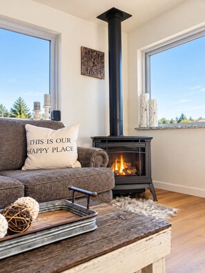 A cozy living room with a fireplace, a sofa with a cushion, and a view of the outdoors. - Lake View Casa (Fort Collins)