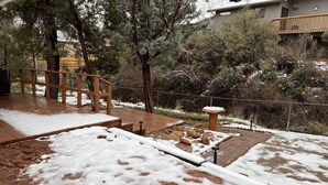 Un pont de fusta amb un camí de pedra, envoltat d'arbres i una tanca.