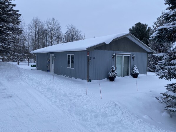 Un bâtiment d’un seul étage, dont le toit est recouvert de neige, et qui possède une porte de garage.