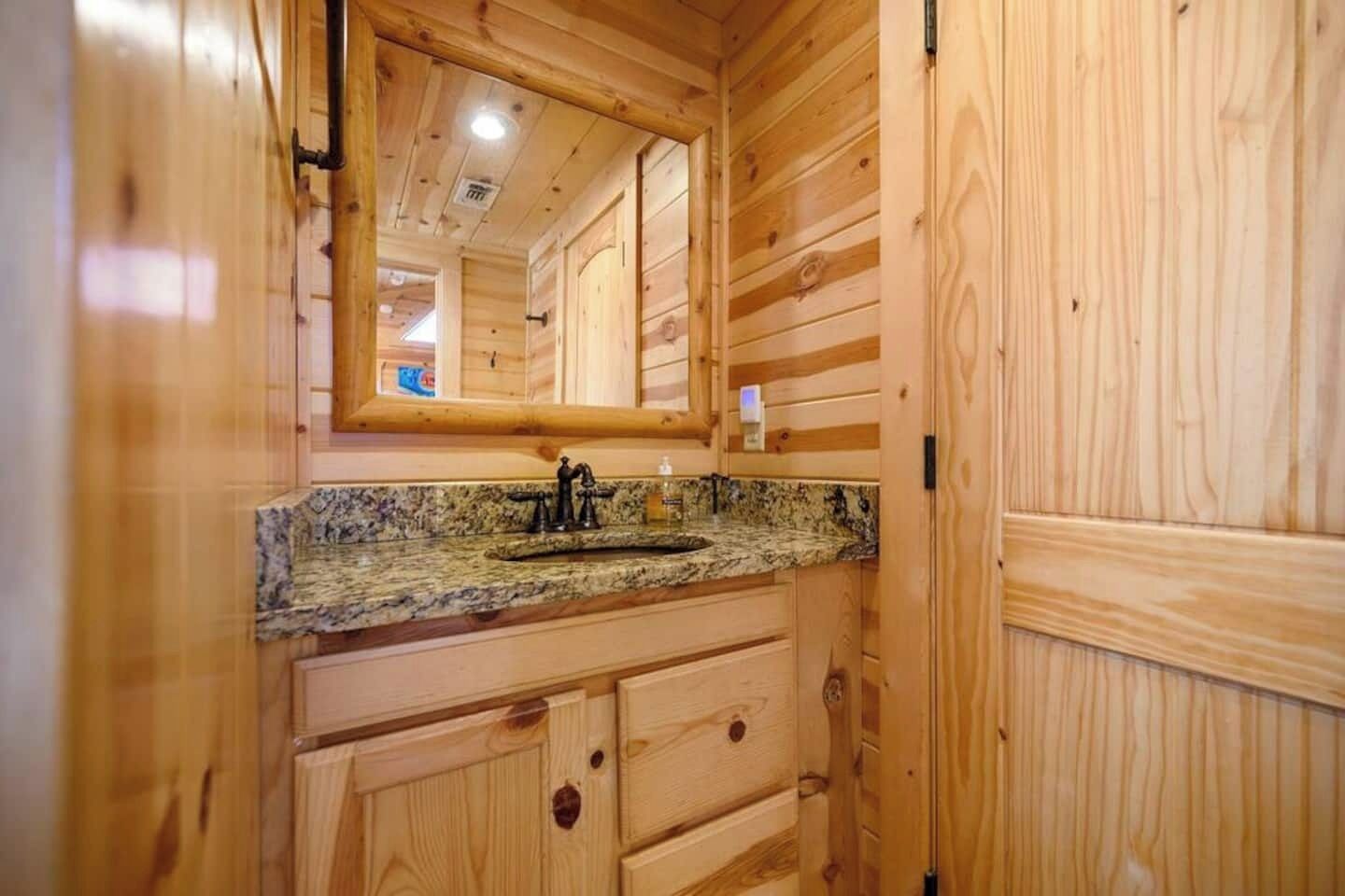 Ein Holzblockhaus-Innenraum mit einer Spüle aus Granit, Holzausstattung und einem Spiegel über der Spüle.