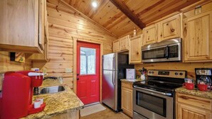 Una cocina con paredes de madera, una puerta roja, electrodomésticos de acero inoxidable y encimeras de granito.