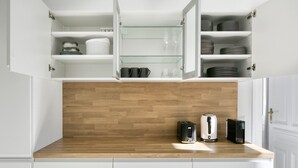 A kitchen with white cabinets, a wooden countertop, and a built-in microwave.