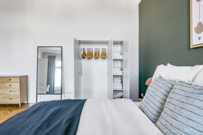 Een slaapkamer met een bed, een kledingkast, een spiegel en een dressoir.