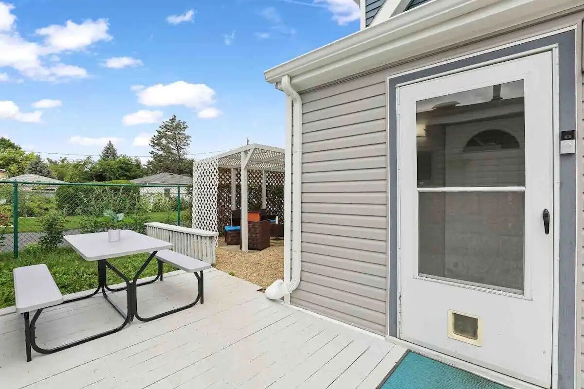 Une terrasse avec une table et des bancs, un espace salon abrité et une porte-fenêtre coulissante.