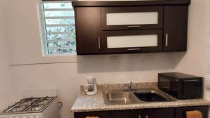 A compact kitchen with a gas stove, oven, microwave, and a double sink.