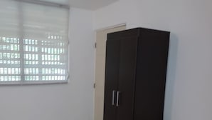 A bedroom with a bed, a wardrobe, and a window with blinds.