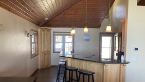 A kitchen with wooden cabinets, a black countertop, and a bar stool.